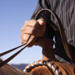man-holding-the-reins-of-horse-close-up-focus-on-hand-101883876-584c7e633df78c491ef4a06a